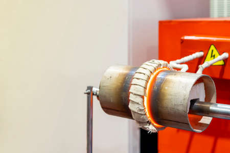 Close up coil and work piece of high volt electric induction heating machine to heat metal pipe or tube in manufacturing industrial workの写真素材