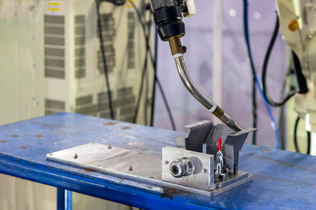 close up workpieces setting on jig fixture with manual quick clamp and torch of electric mig robot...