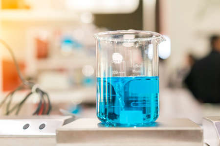 Close up of beautiful vortex blue colorful chemistry liquid in beaker laboratory flask on magnetic stirrer or mixer machine for scienceの写真素材