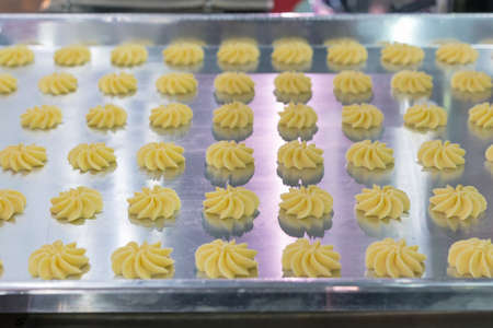close up dough or cream on tray of automatic biscuit or sweets making machine in production line for...