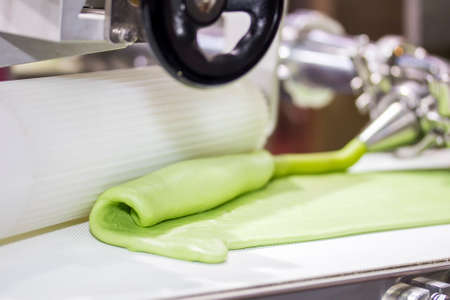 close up rolled dough after mix cream extrude form nozzle on belt conveyor of automatic food making machine for chinese or asian food (steamed stuffed buns) by high technology industrial manufacturingの写真素材