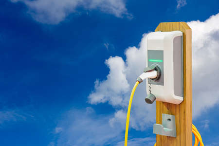 electric vehicle charging (Ev) station and plug of power cable supply for Ev car on blue sky and cloud background with copy spaceの写真素材