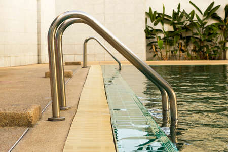 metal staircase in school swimming pool with sunny reflectionsの写真素材