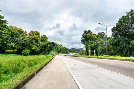 Beauty empty highway road with lamp post and tree on cloudy sky backgroundの写真素材