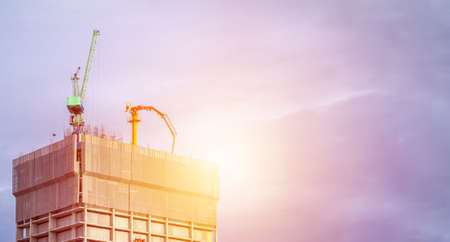 A huge crane at hotel or condo building construction site with blue sky and bright sunlight