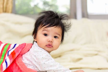 portrait asian cute baby in a blanket crawl or wake up on the bed in roomの写真素材