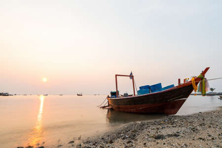Beautiful seascape sunset with golden sunshine and fishing boat long exposure.