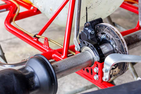 close up standard rear axle and bearings wheel hubs and hydraulic caliper disc brake unit of mini racing car sports go kart or scooter at service stationの写真素材