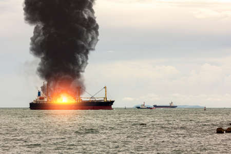 Large general cargo ship for logistic import export goods and other the explosion and had a lot of fire and smoke at seaの写真素材
