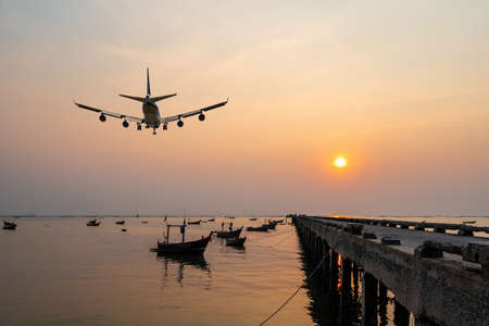 rear image commercial passenger aircraft or cargo airplane fly over fishing wood boat floating in...