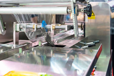 close up roll plastic film set on adjustment bar of wrapping or packing machine for goods or product...