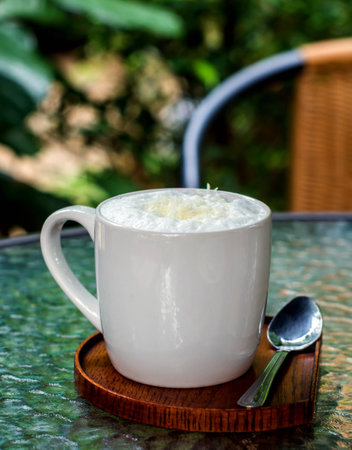 a cup of coffee with cream and white chocolate flakes with blur background.の写真素材