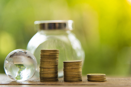 Growing Business Growth and Financial Cultivation of Plants from Coins in Glass Bottles on Green Backgroundの写真素材