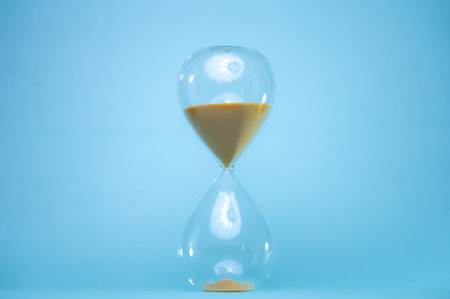 Telling time with an hourglass with sand flowing within a distance. Transparent hourglass.
