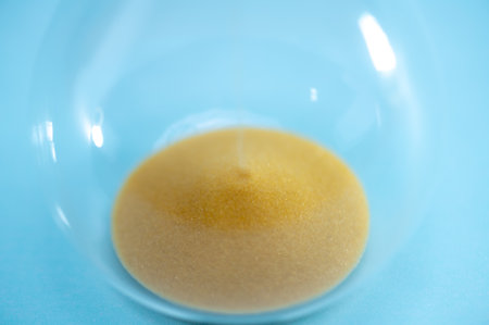 Telling time with an hourglass with sand flowing within a distance. Transparent hourglass.