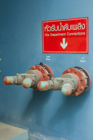 Two Fire Department Connection on blue wall background. Foreign text on red wall is the name of fire equipment.の写真素材