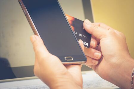 Shopping Online Concept : Woman holding credit card to use paying on smartphone with laptop...
