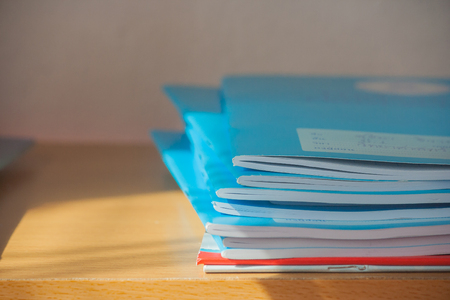 Stack of blue notebooks on wooden table with sunlight.の写真素材
