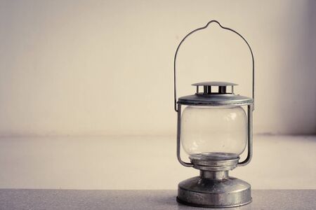 Vintage kerosene oil lantern lamp standing on cement floor with white wall background. (Vintage filter effect)の写真素材