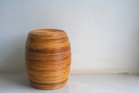 Round brown wicker chair in vintage style on cement floor in white room with natural light.の写真素材