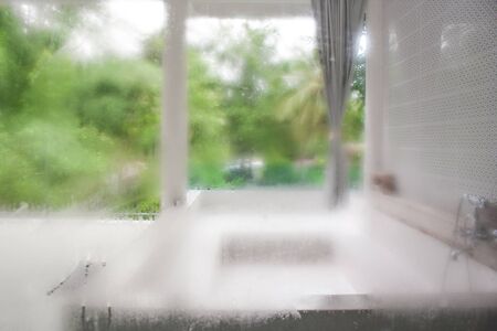 Abstract blurred water drops on transparent window with outdoor bathroom background.の写真素材