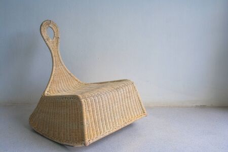 Brown wicker chair in vintage style on cement floor in white room with natural light.の写真素材
