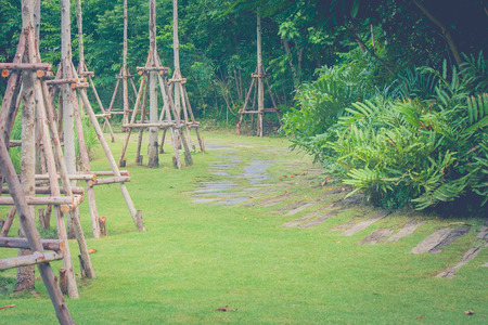 Wooden footpath on green grass with green garden background. (Vintage filter effect)の写真素材