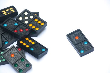 Close up black color dominoes with colorful dot pieces lie on white background.の写真素材