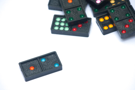 Close up black color dominoes with colorful dot pieces lie on white background.の写真素材