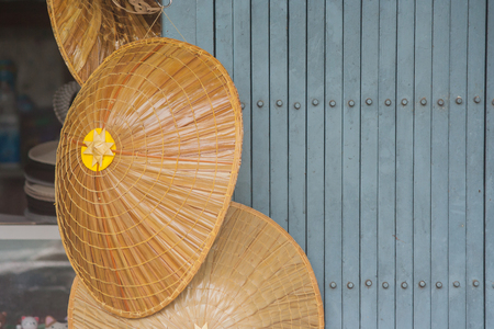 Close up bamboo weave hat hanging on metal door.の写真素材