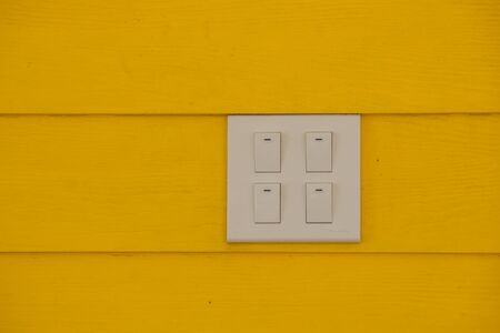Close up white electricity switch or light switchon yellow color wall background. (Soft Focus)の写真素材