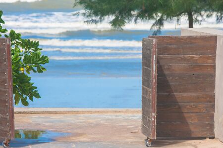 Close up open wooden door to access the beach with sea view and palm tree background.の写真素材