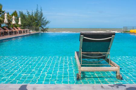 Vacation and Relaxation Concept : Daybed beside swimming pool in the resort with sea and blue sky background.の写真素材