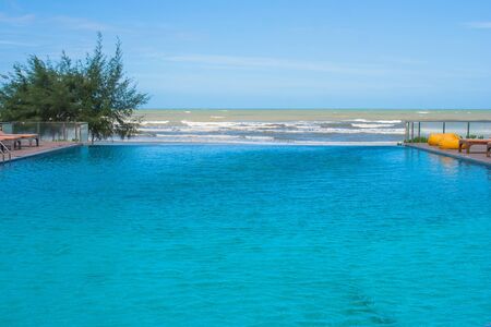 Swimming pool in modern design at hotel with sea view and blue sky background.の写真素材