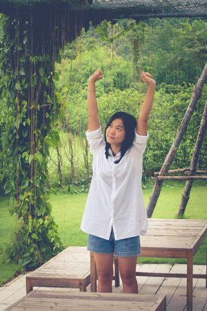 Relaxation Concept : Asian woman wear white shirt and stretch in the garden. (Vintage filter effect)の写真素材