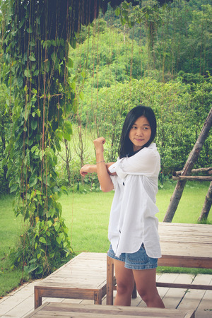 Relaxation Concept : Asian woman wear white shirt and stretch in the garden. (Vintage filter effect)の写真素材