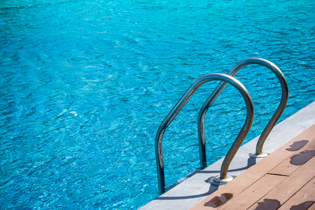 Metal grab bar ladder in blue water swimming pool at the resort.の写真素材