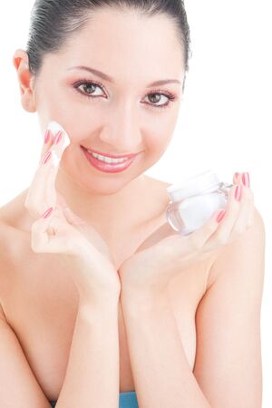 Woman applying cream to her face on the white background の写真素材