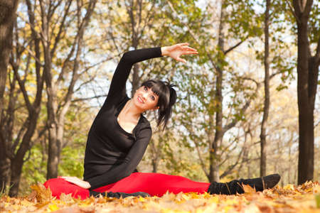 Pretty woman doing yoga exercises in the autumn park の写真素材