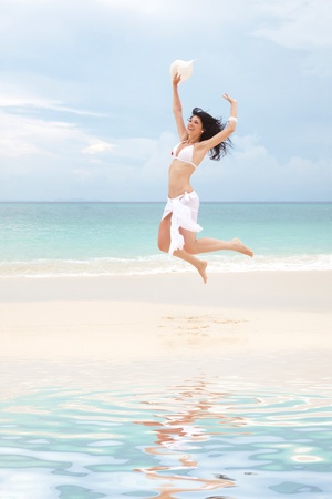 happy young woman jumping in the beach の写真素材