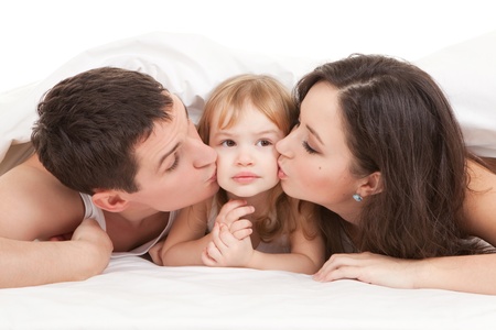 Happy family, mother, father and daughter on the white bed の写真素材