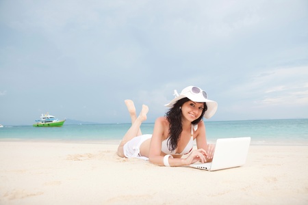 Cute woman with white laptop on the summer beachの写真素材