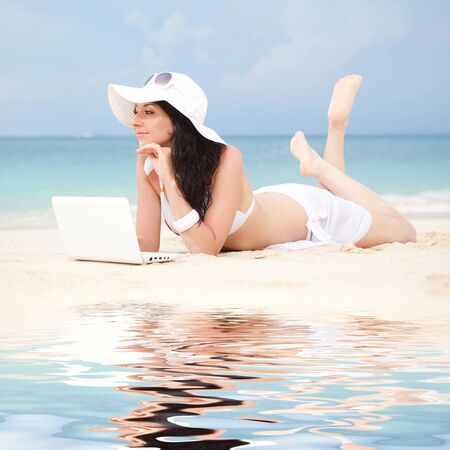 Cute woman with white laptop on the summer beachの写真素材