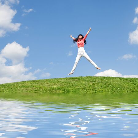 pretty young woman jumping on green grass の写真素材
