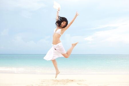 happy young woman jumping on the beach of seaの写真素材