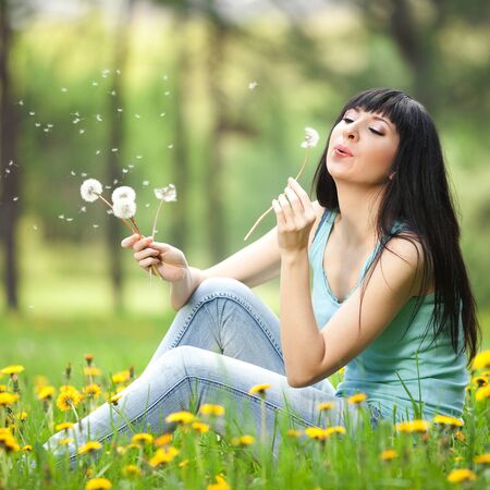 Cute woman in the park with dandelionsの写真素材