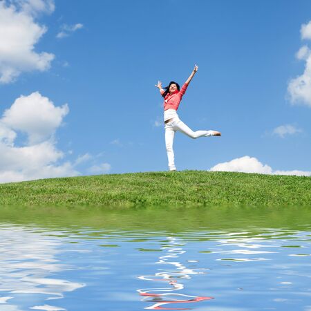 pretty young woman jumping on green grassの写真素材