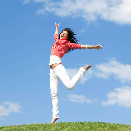 pretty young woman jumping on green grassの写真素材