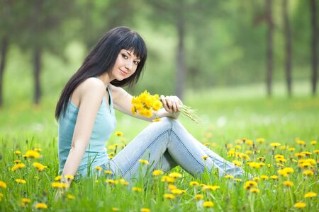 Cute woman in the park with dandelionsの写真素材