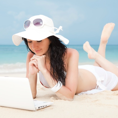 Cute woman with white laptop on the summer beachの写真素材